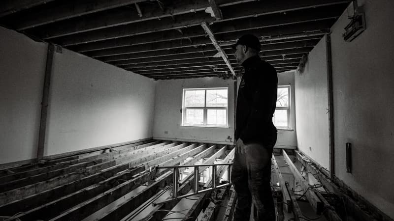Black and white photo on site during a back-to-brick strip-out, with floor joists exposed and ceilings removed