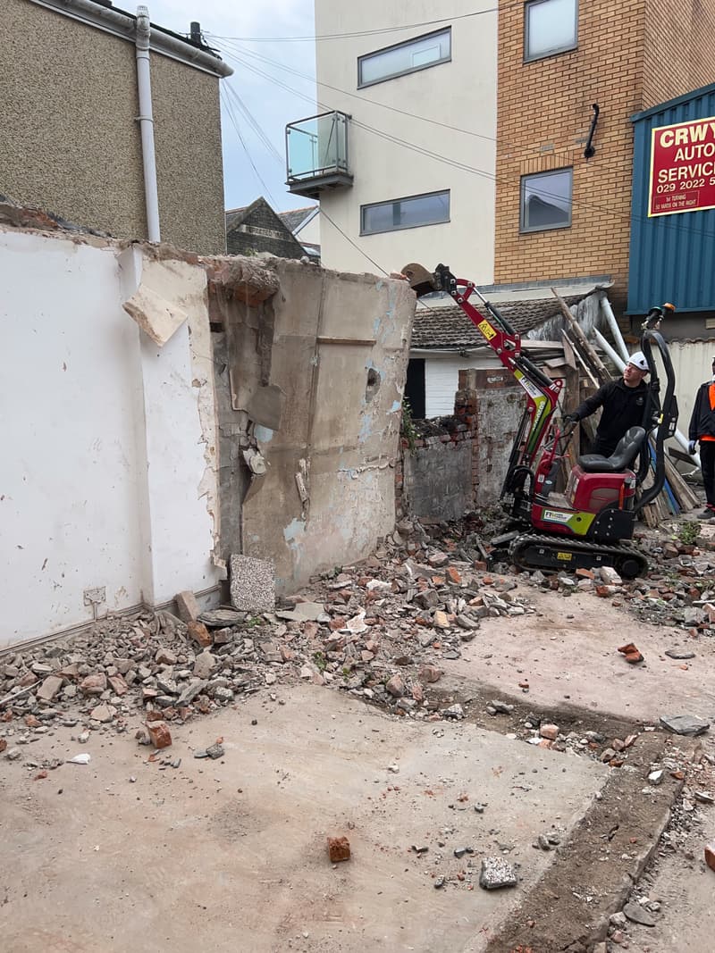 Mini excavator demolishing the rear annex of a Cathays terrace
