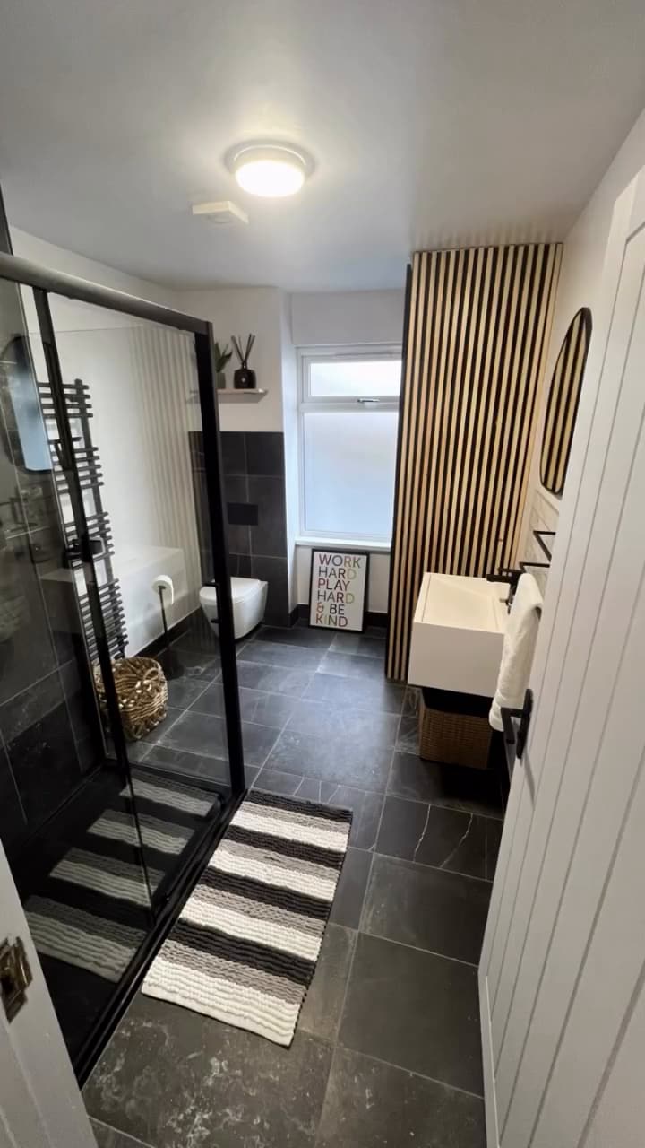 Striking bathroom with black-framed walk-in shower, slate floor and oak slat panelling