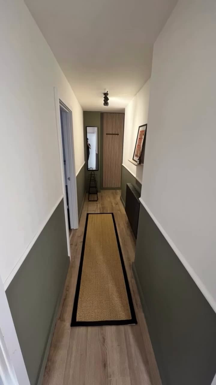 Hallway with two-tone green and white walls, oak-effect floor and runner
