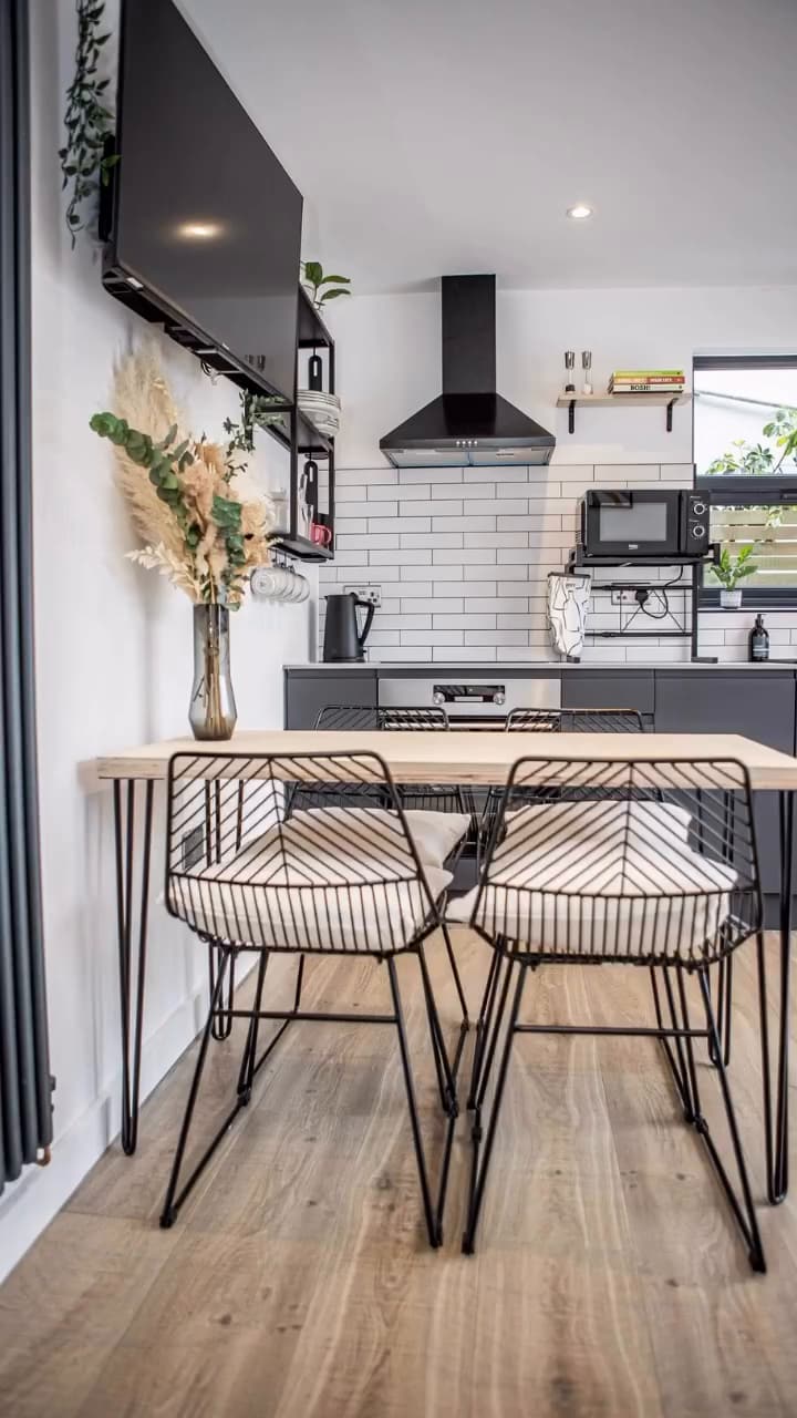 Kitchen with white metro tiles, black fittings and breakfast bar with rattan stools