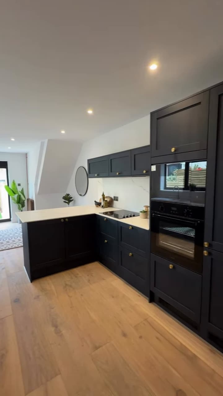 Navy shaker kitchen with integrated ovens and oak floor