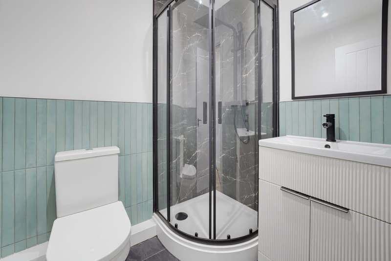 Shower room with sage green wall panelling, quadrant enclosure and fluted vanity unit